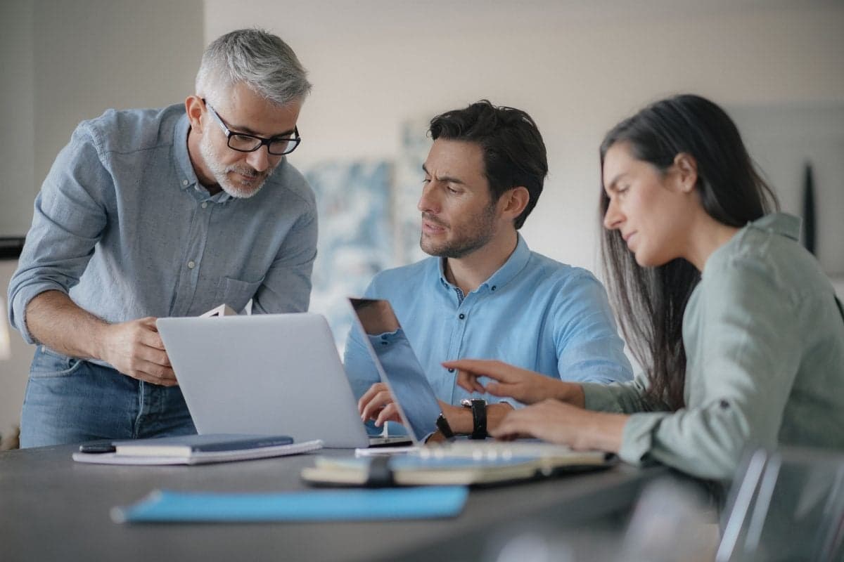 Young colleagues with older boss working with computers