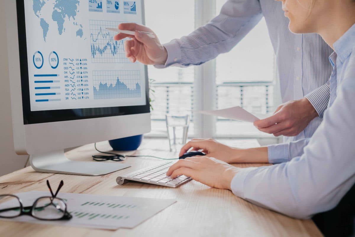 Two people analyzing stock market investment strategy on compute