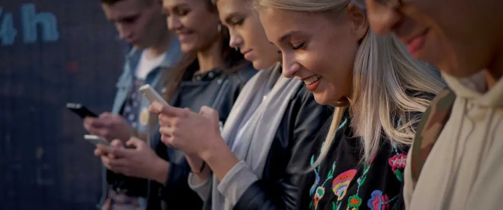 A group of millenials using phone, showing their more modern thinking mindset