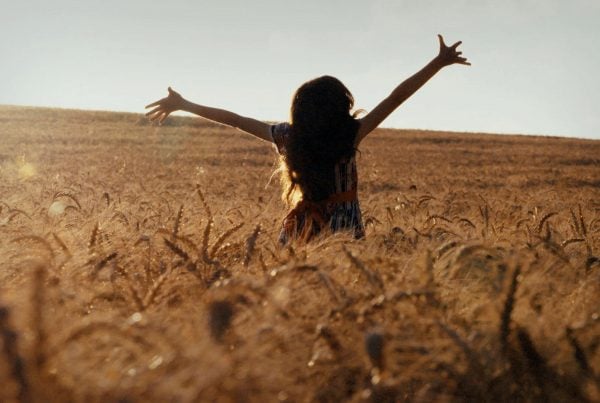 Girl in wheat field arms up
